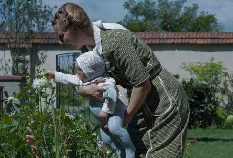 Mulher com bebê no colo mexendo em plantas.