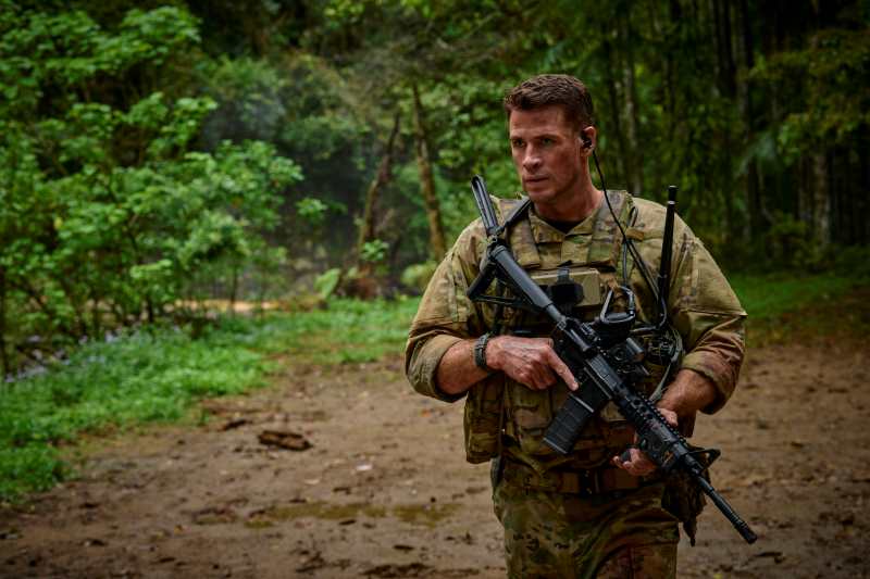 Soldado com espingarda na mão numa mata