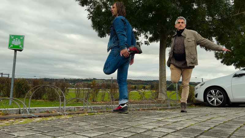 Dois homens alongam suas pernas na rua.