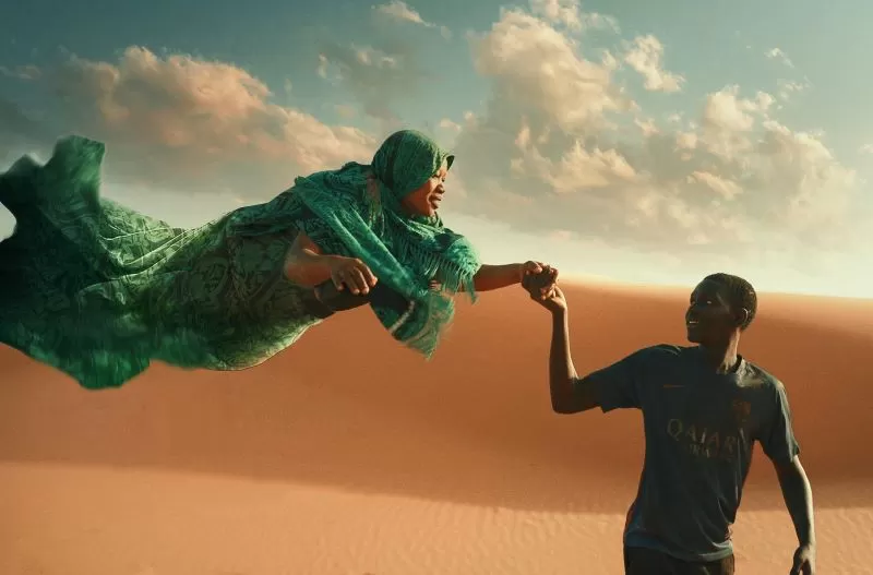 Menino conduz em sua mão uma mulher que levita no deserto